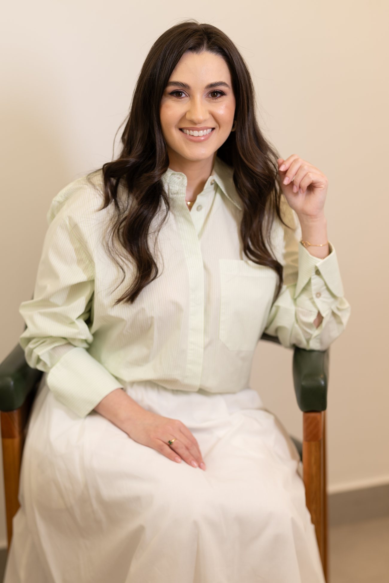 Dra. Fernanda Galvani sentada no consultório, sorrindo
